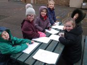 6 Children sat around a picnic bench outside, with their drawing of daffodil bulbs in front of them.