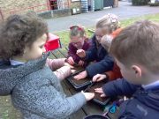 Children patting down the soil after planting the seeds.